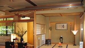 A traditional Japanese-style room with tatami flooring, a low table with a tea set, a shoji screen, and a small statue. - Gero Onsen Kissenkan Chikusuitei (Gero)