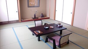 A traditional Japanese room with tatami flooring, a low table with cushions, a framed picture on the wall, and sliding doors. - Gero Onsen Kissenkan Chikusuitei (Gero)