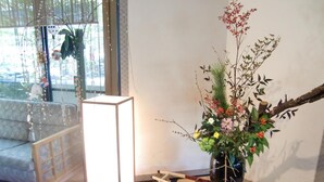 A room with a traditional Japanese-style tatami mat floor, a wooden table with a light fixture, and a decorative plant arrangement. - Gero Onsen Kissenkan Chikusuitei (Gero)