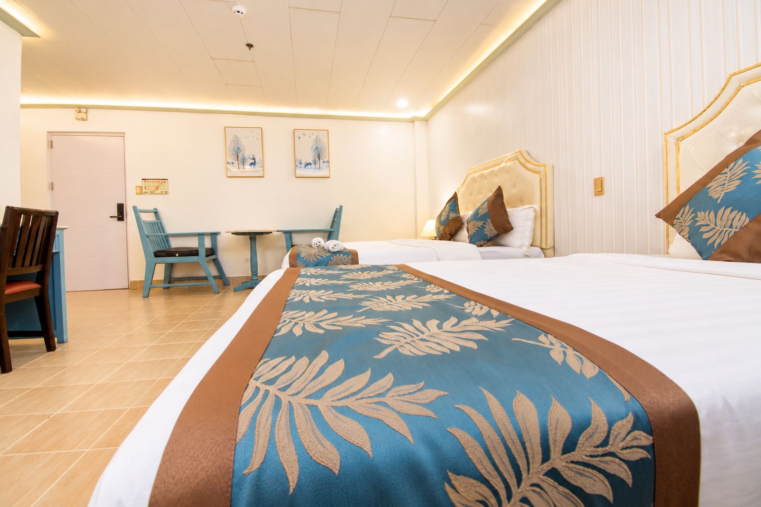 A hotel room with a bed, a desk, and two chairs.