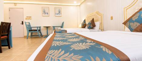 A hotel room with a bed, a desk, and two chairs.