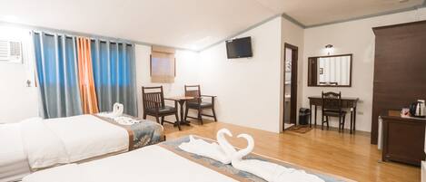 A hotel room with two beds, a desk, a chair, and a television.