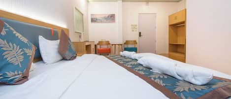 Una habitación de hotel con cama, escritorio, silla, armario y un cuadro en la pared.