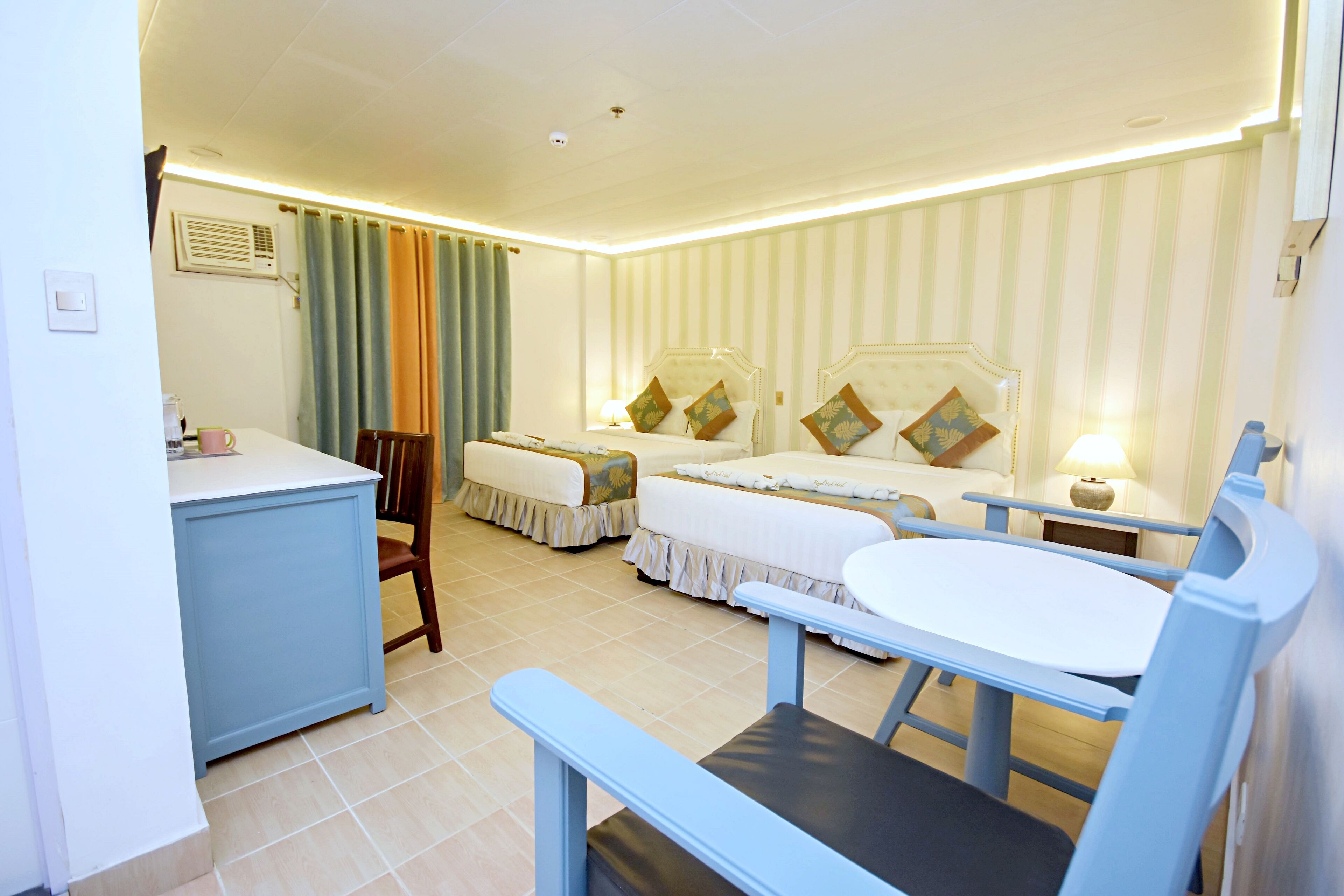 Une chambre d’hôtel avec deux lits, un bureau et une chaise.
