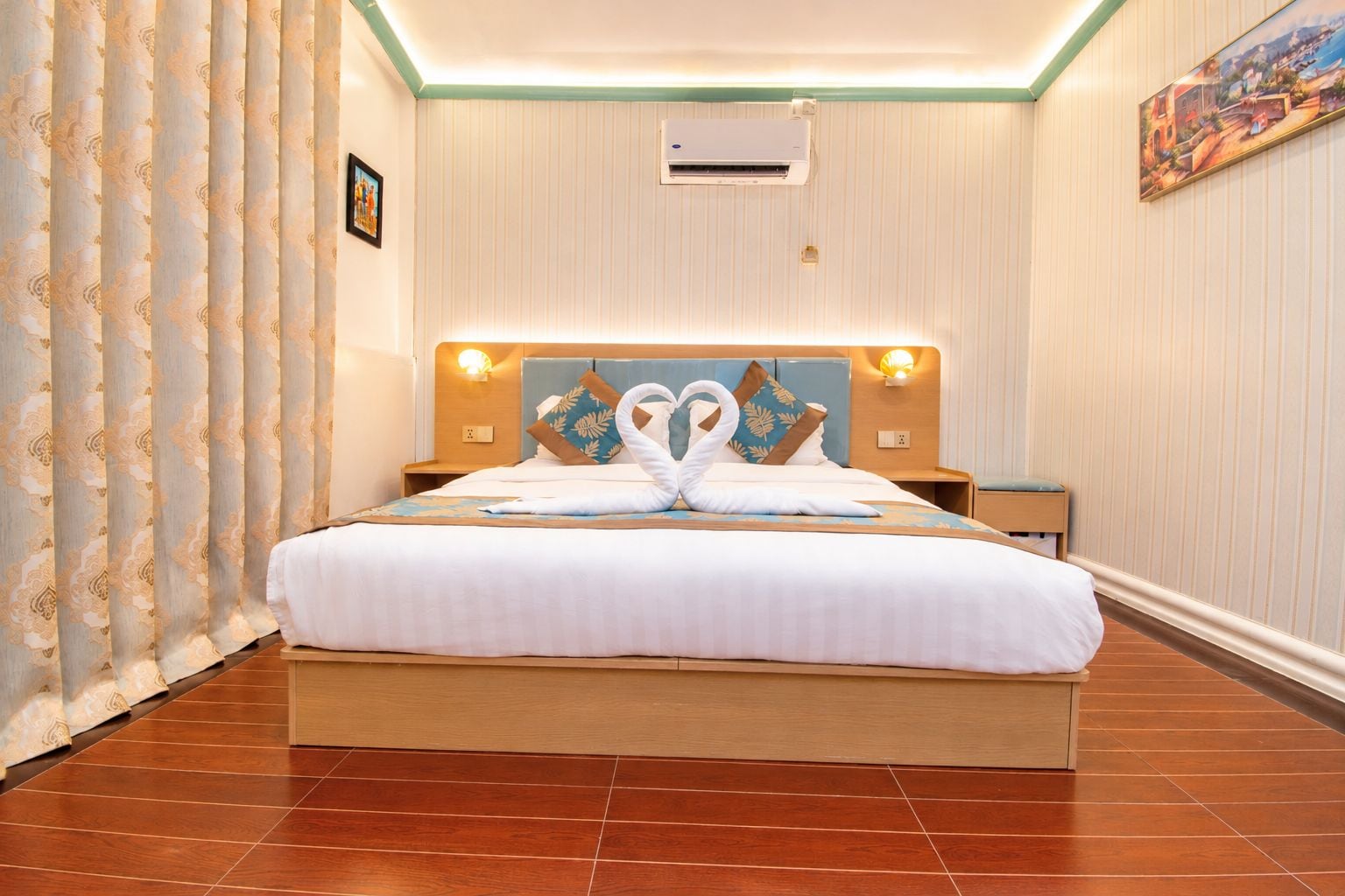 Una habitación de hotel con una cama grande, aire acondicionado de pared y un cuadro en la pared.
