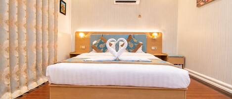 Una habitación de hotel con una cama grande, aire acondicionado de pared y un cuadro en la pared.