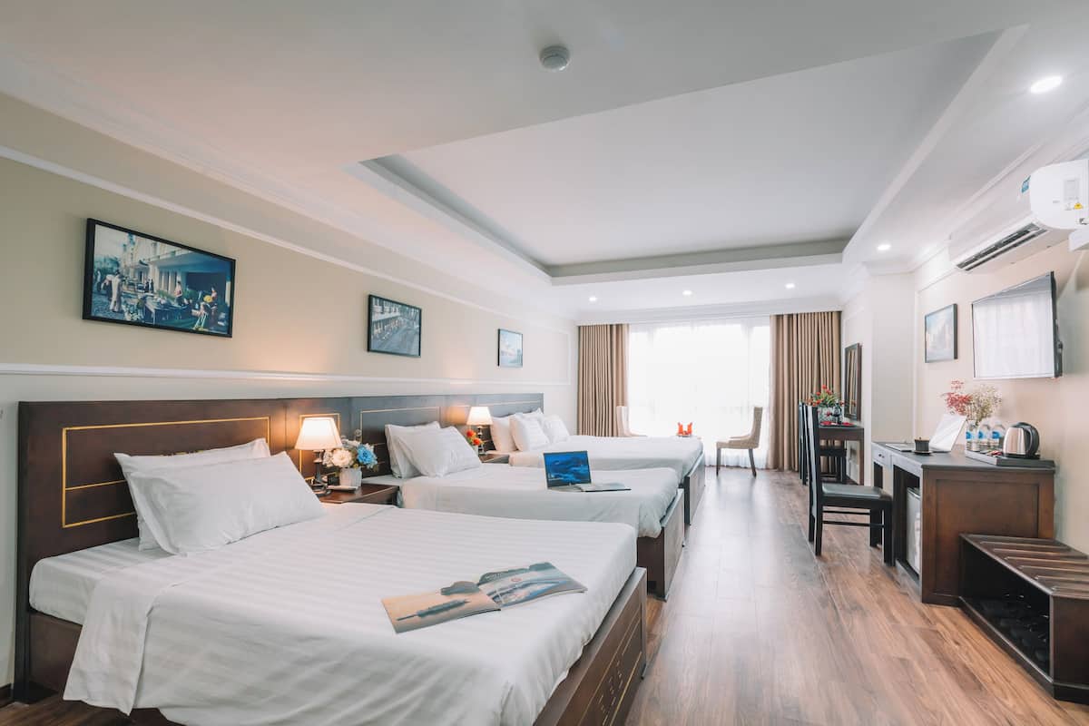 A hotel room with two beds, a desk, a chair, and a dining area.