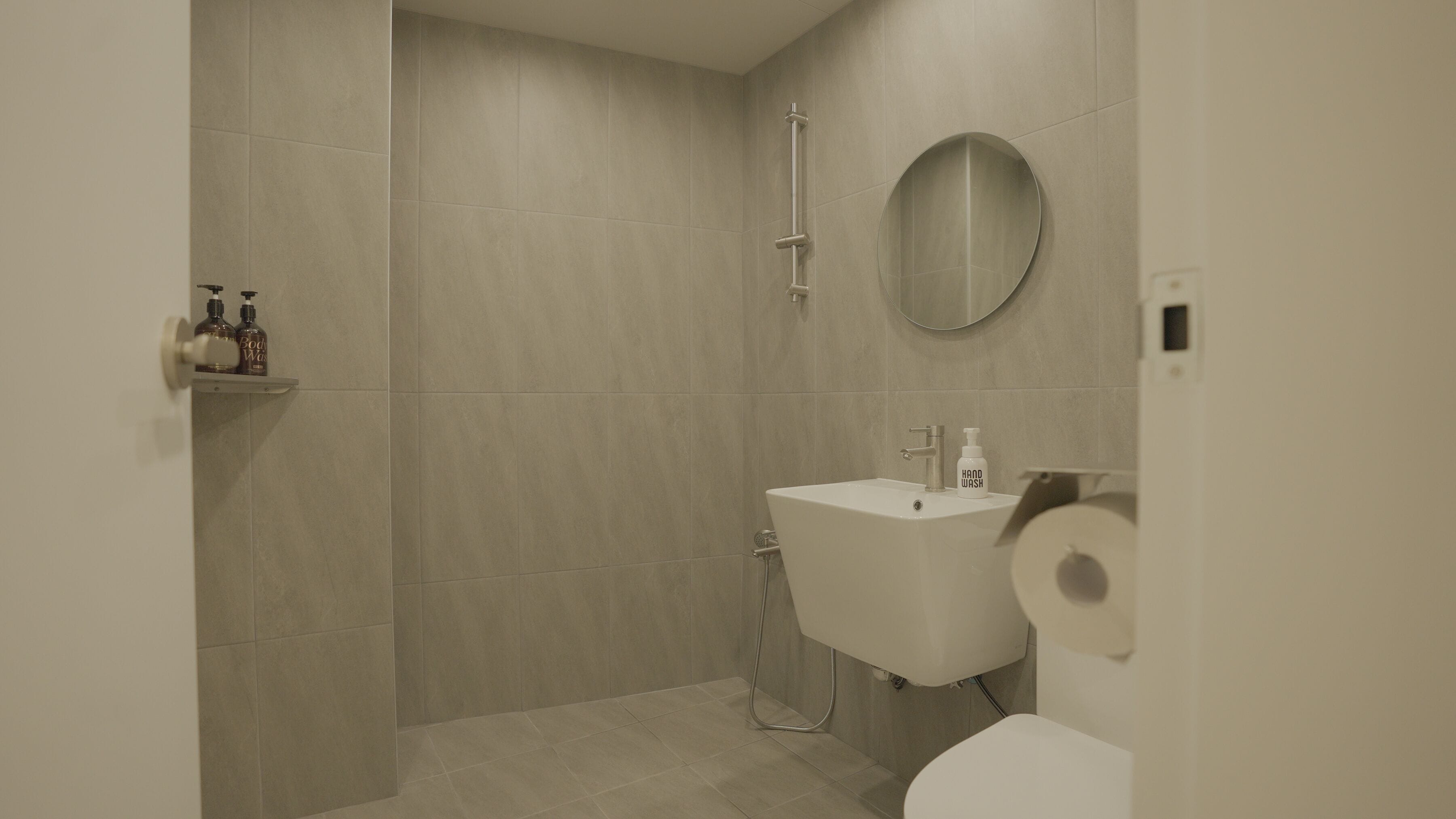 A modern bathroom with a shower, sink, and toilet.