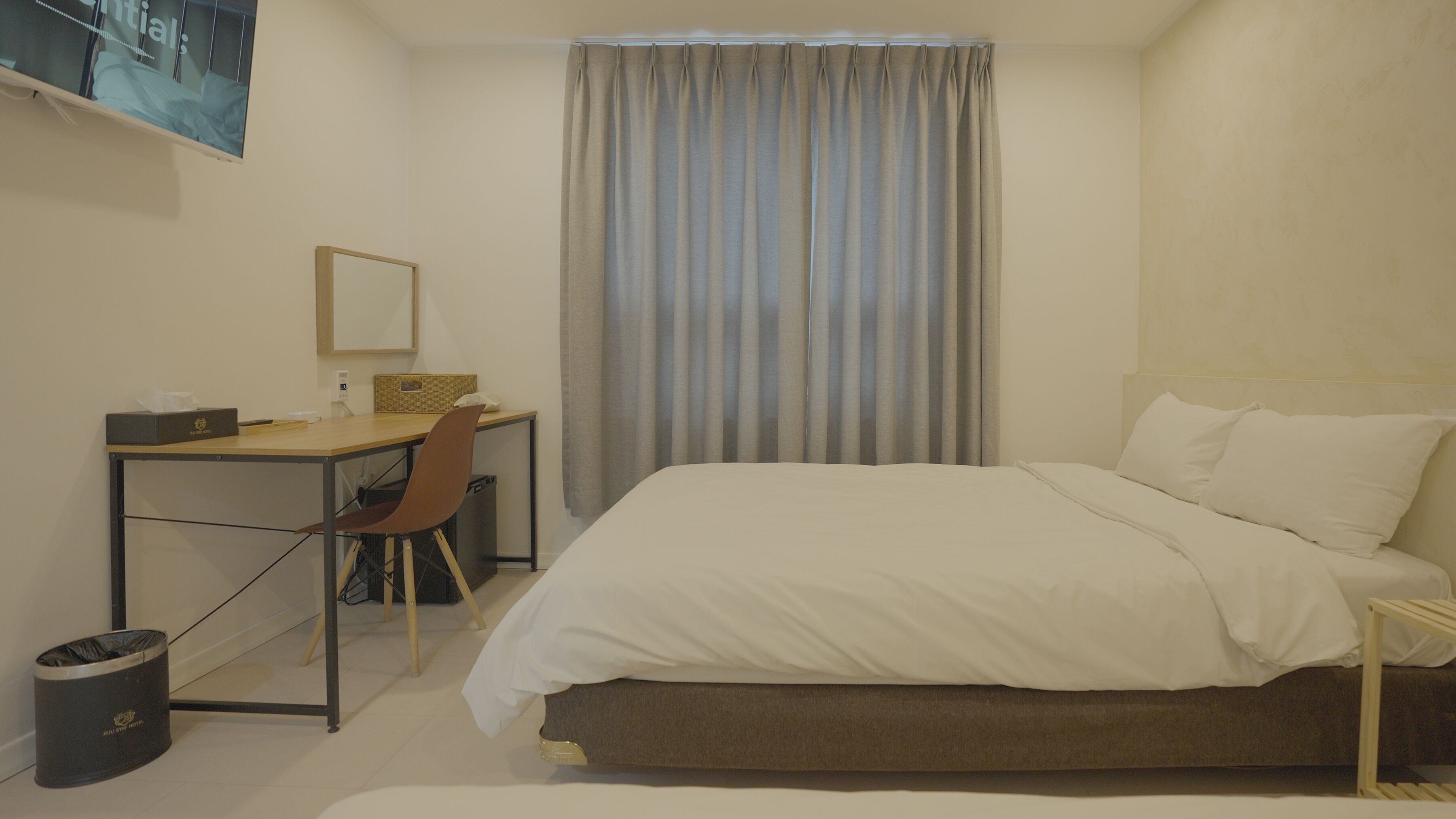 Une chambre d’hôtel équipée d’un lit, d’un bureau, d’une chaise, d’une télévision et d’une fenêtre avec des rideaux.