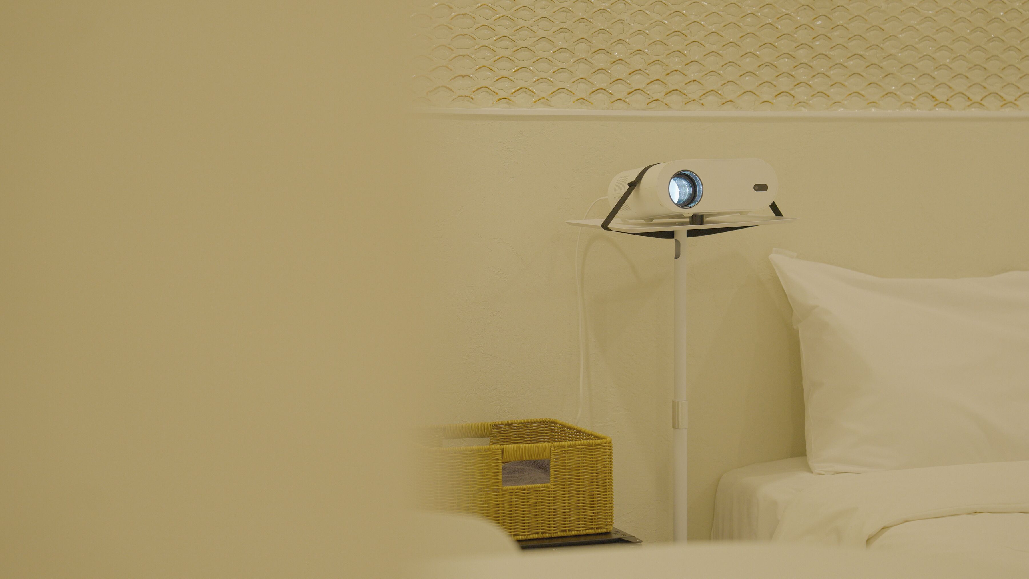 Una habitación con una cama, una lámpara de pie y una pequeña cesta de mimbre.