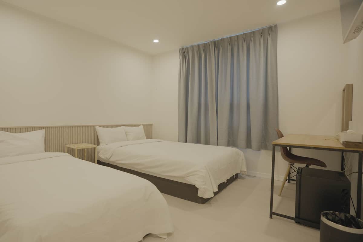 A hotel room with two beds, a desk, and a chair.