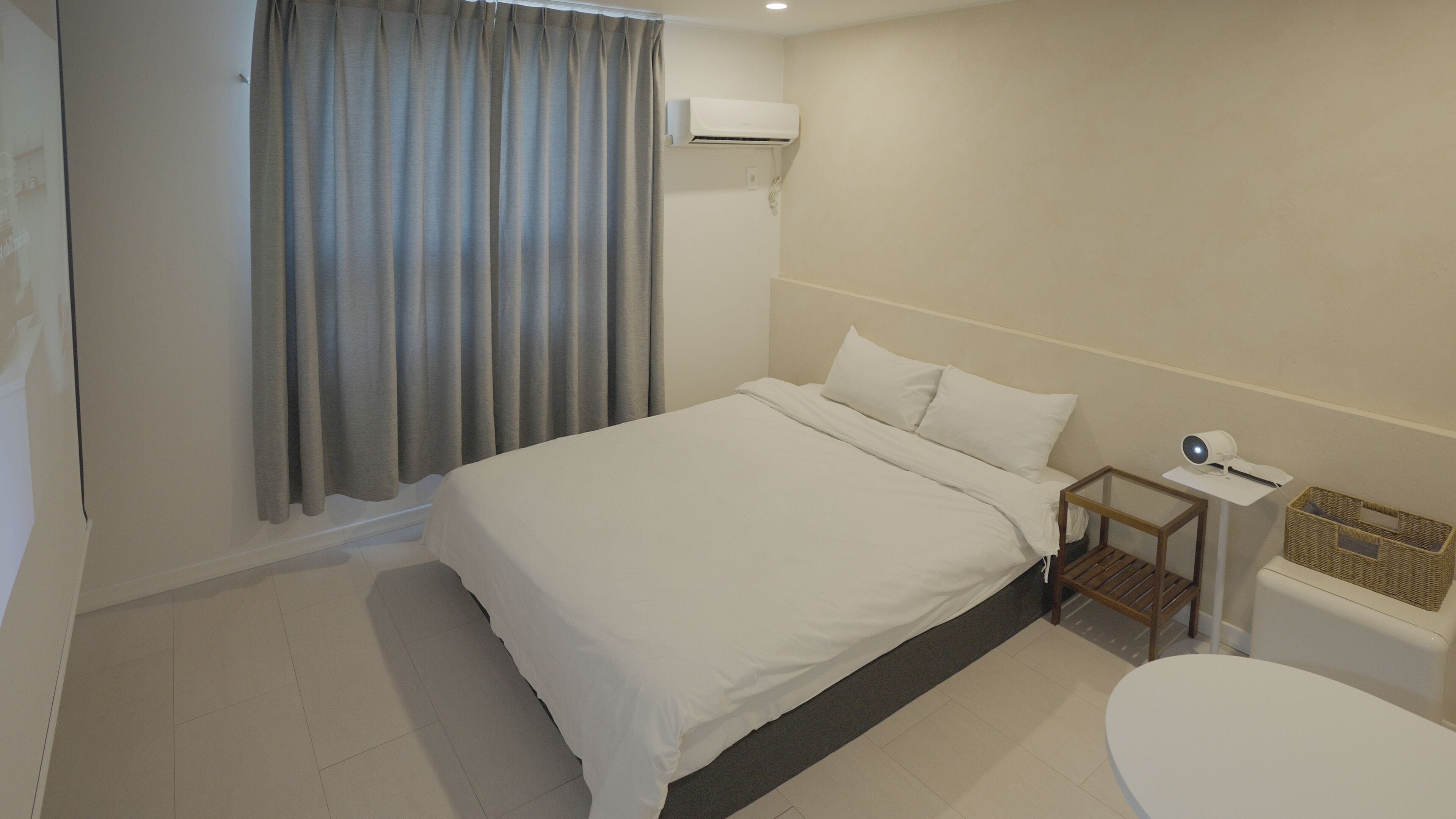 Une chambre d’hôtel avec un lit, une petite table de chevet avec une lampe, des toilettes et une fenêtre avec des rideaux.