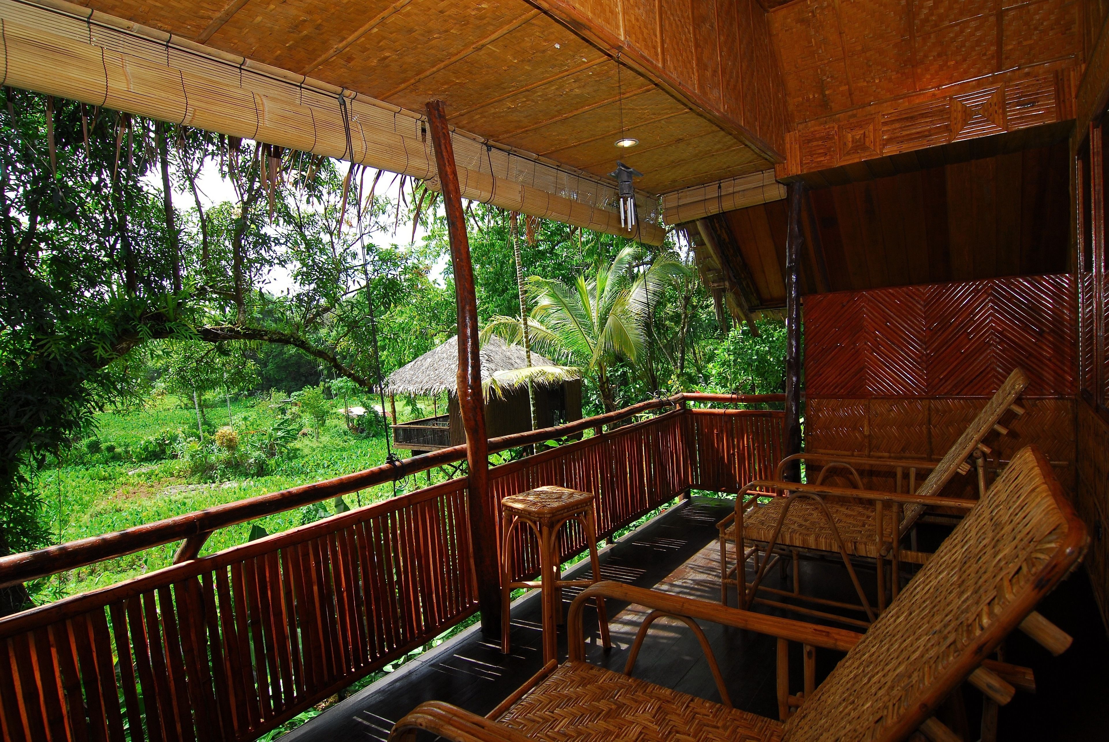 A wooden deck with wicker furniture overlooking a lush garden.
