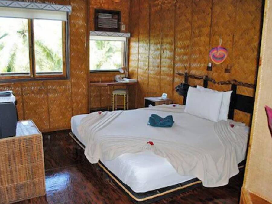 A wooden-paneled room with a bed, a desk, and a window.