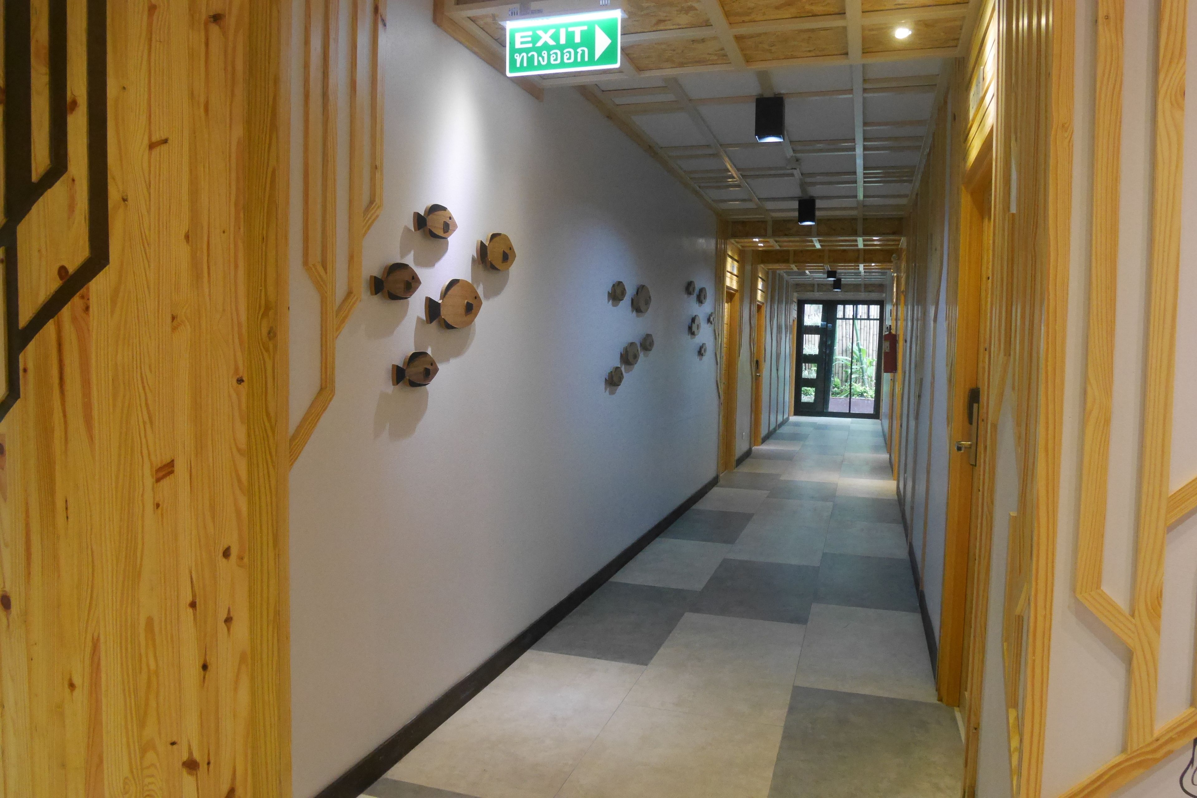 A hallway with wooden paneling, a green EXIT sign, and a series of fish-shaped decorations on the wall.