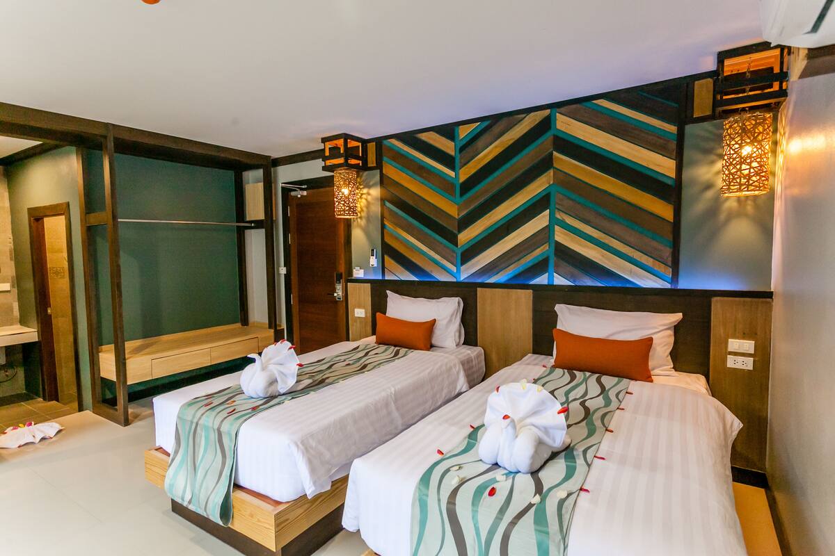 A hotel room with two beds, a large mirror, and a decorative wall with a chevron pattern.