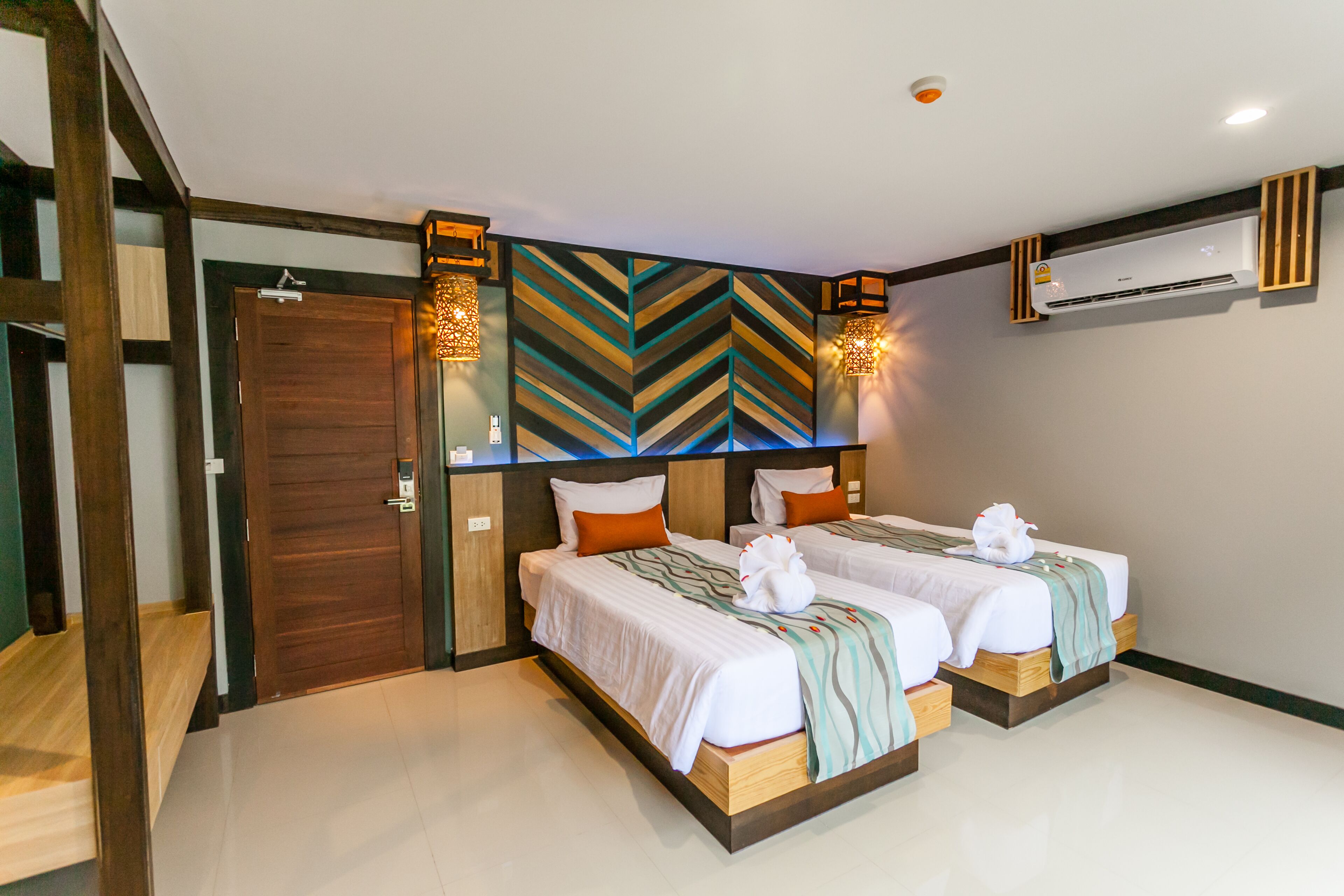 Ein Hotelzimmer mit zwei Betten, einer Holztür und einem modernen Wanddesign.