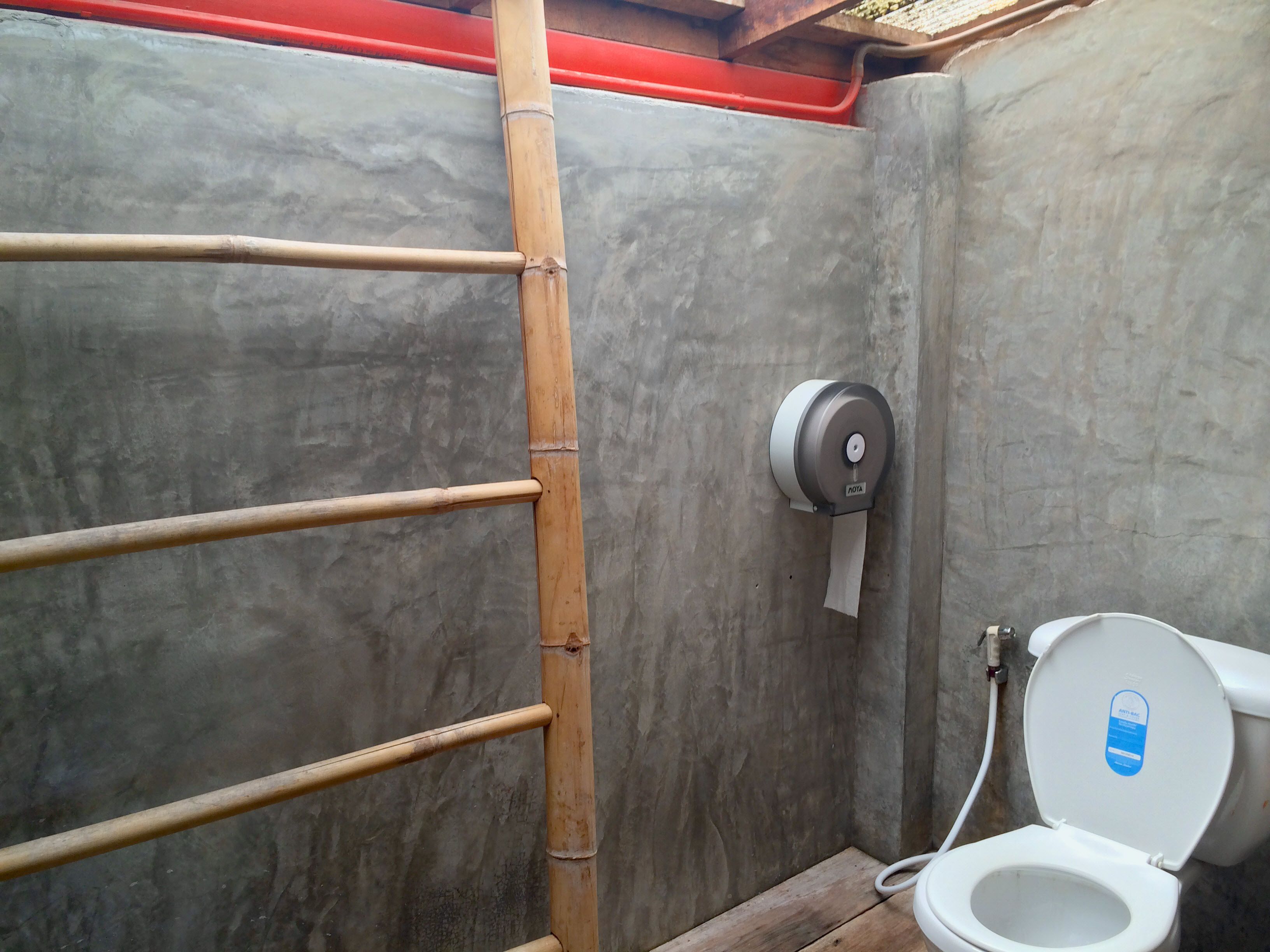 A bathroom with a toilet, a hand dryer, and a bamboo ladder.