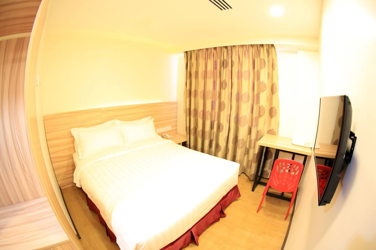 Ein Hotelzimmer mit Bett, Schreibtisch, Stuhl und Fernseher.