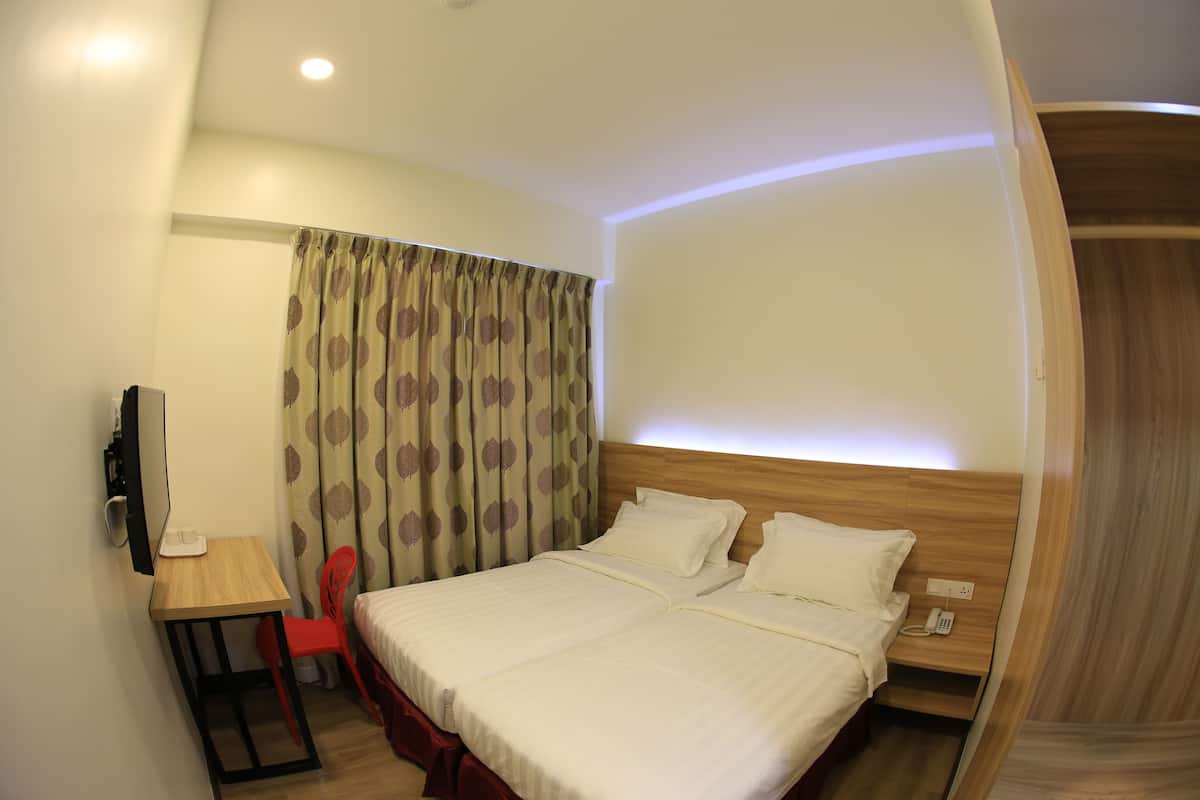 Ein Hotelzimmer mit Bett, Schreibtisch, Sessel, Fernseher und Telefon.