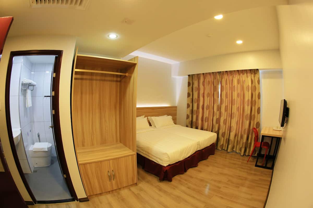 Ein Hotelzimmer mit einem Bett, einem Holzschrank, einem Schreibtisch mit Stuhl und einer Duschkabine.