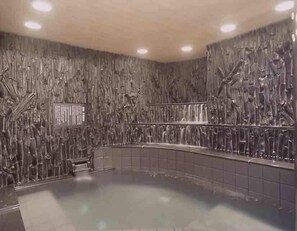 A spa area with a stone wall, a curved bench, and a small pool. - Capsule Hotel Wellbe Sakae - Caters to Men (Nagoya)