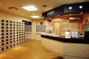 A hotel reception area with a counter, a price list, and a row of lockers. - Capsule Hotel Wellbe Sakae - Caters to Men (Nagoya)