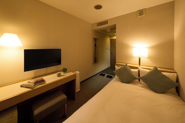 A hotel room with a bed, desk, TV, and lamps. - Hotel Resol Machida (Machida)