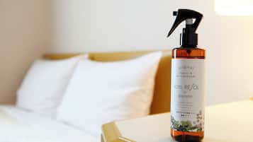 A hotel room with a bed, a nightstand, and a bottle of Hotel Resol air freshener on the nightstand.