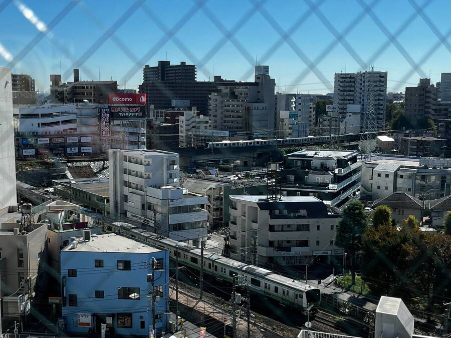 A cityscape with modern buildings, a train, and a visible docomo sign.