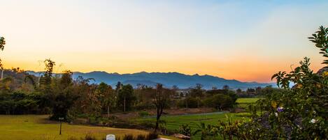 A swimming pool with a water slide, surrounded by greenery and a view of distant mountains.