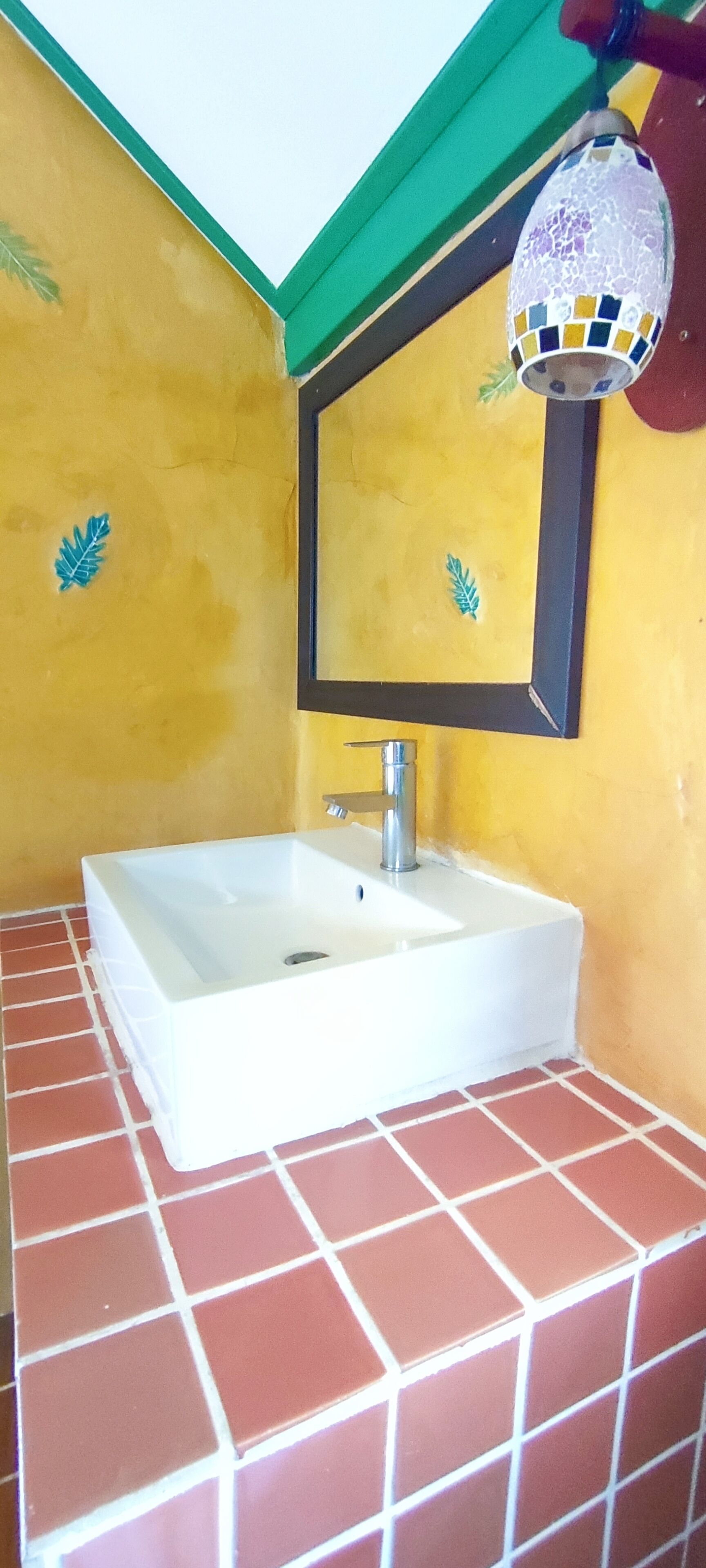 A bathroom with a white sink, green and yellow walls, and a tiled floor.