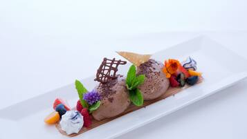 Ein Dessert mit Schokoladeneis und Obst als Garnitur auf einem weißen Teller.
