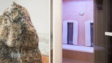 Experience the unique blend of natural and modern elements in this contemporary space, featuring a rock formation and a sleek bathroom with two sinks and a clock.