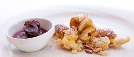 Un plato de postre con un bol de compota de fruta oscura y una pila de hojaldre desmenuzado espolvoreado con azúcar glas.