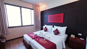 A hotel room with two beds, a large window, a wooden floor, and a red accent wall. - River Kwai Hotel (Kanchanaburi)