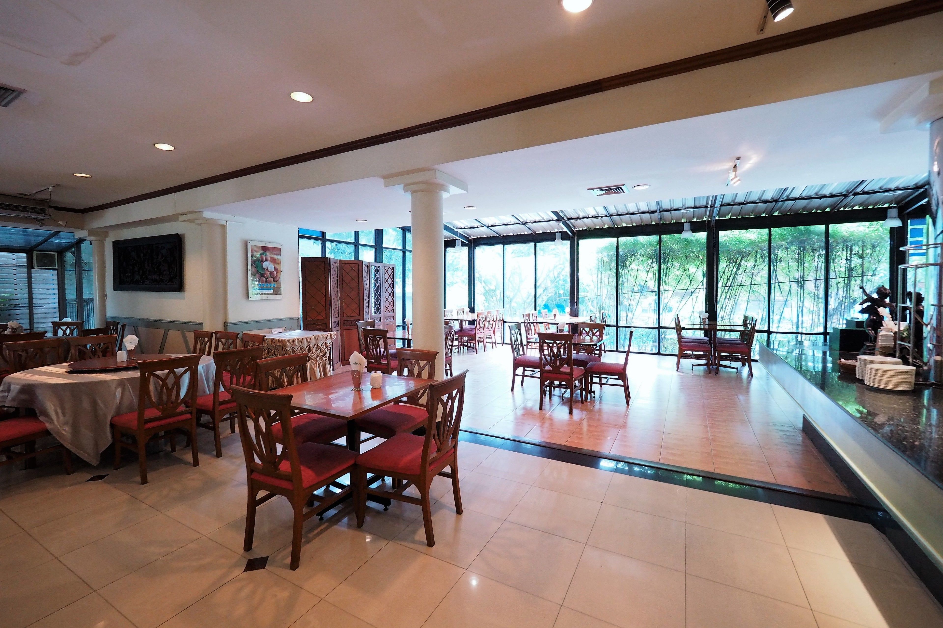 A spacious restaurant with high ceilings, large windows, and wooden tables and chairs.