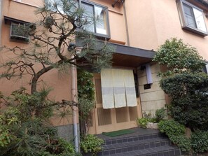 A building with a wooden entrance gate, a small step leading up to the door, and a window with a view of the sky.