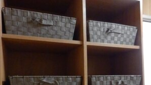 Un mueble de madera con varios estantes, cada uno sosteniendo una cesta tejida.