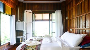 A wooden-paneled room with a bed, a small table, and a window with curtains. - Bhuvarin Resort (Ko Chang)