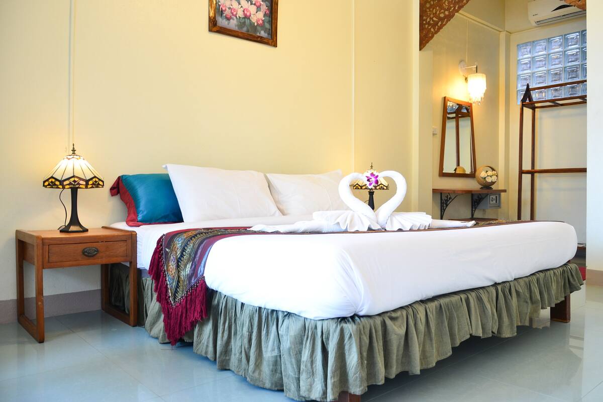 A neatly made bed with white linens and a heart-shaped decoration on the pillows.