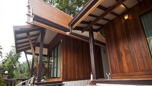 A wooden exterior with a covered patio area, outdoor seating, and a large decorative pot. - Bhuvarin Resort (Ko Chang)