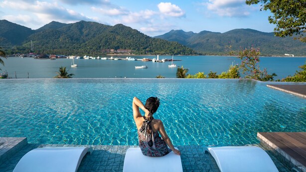 A woman sitting by a pool with a view of boats and mountains. - Bhuvarin Resort (Ko Chang)