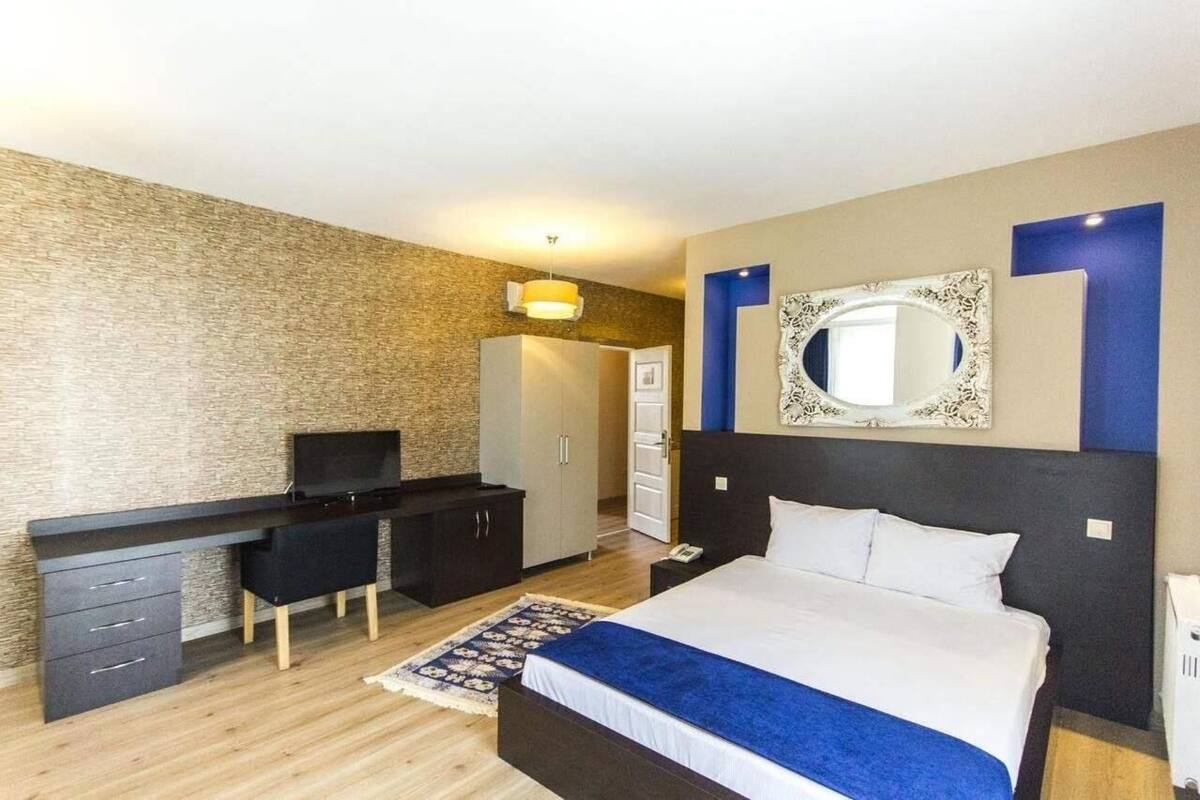A modern hotel room with a bed, a desk, and a wardrobe.