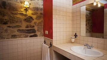 A bathroom with a stone wall, a white sink, and a red accent wall.