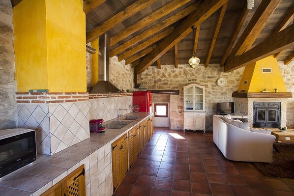 Una cocina rústica con vigas de madera a la vista, una pared de piedra y una chimenea.