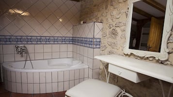 A bathroom with a freestanding bathtub, a white vanity with a mirror, and a tiled floor.