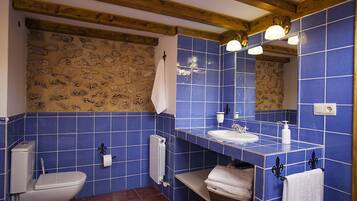 A bathroom with blue tiles, a white toilet, a sink, and a mirror.