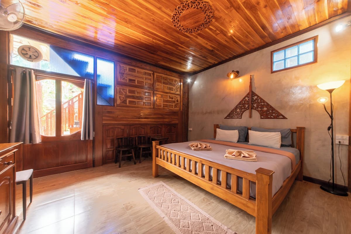 A wooden bedroom with a bed, a desk, and a chair.
