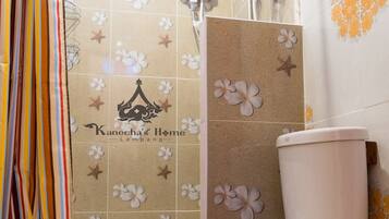 Un baño con inodoro, ducha y paredes de azulejos con diseños florales.